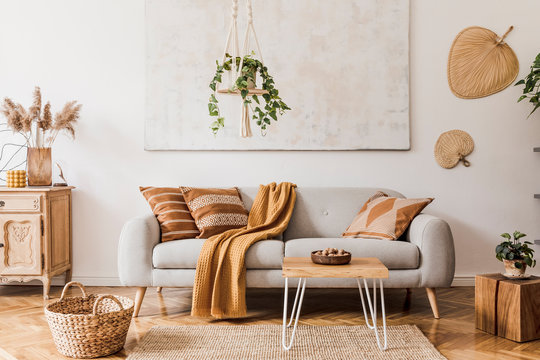 客厅室内时尚的波西米亚风格，配有设计灰色沙发、木制茶几和通讯器