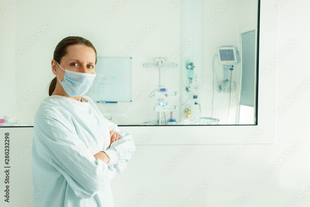 Nurse near window of intensive care newborn room