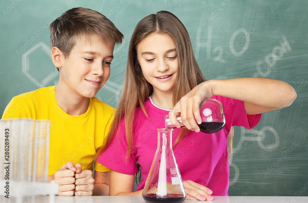男孩和女孩在做化学实验。把液体倒进烧杯