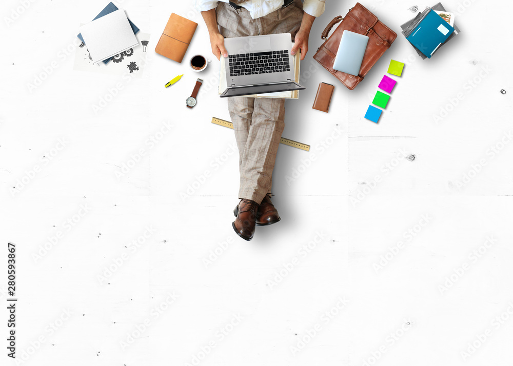 年轻人坐在地板上，拿着书和笔记本电脑工作，商业理念