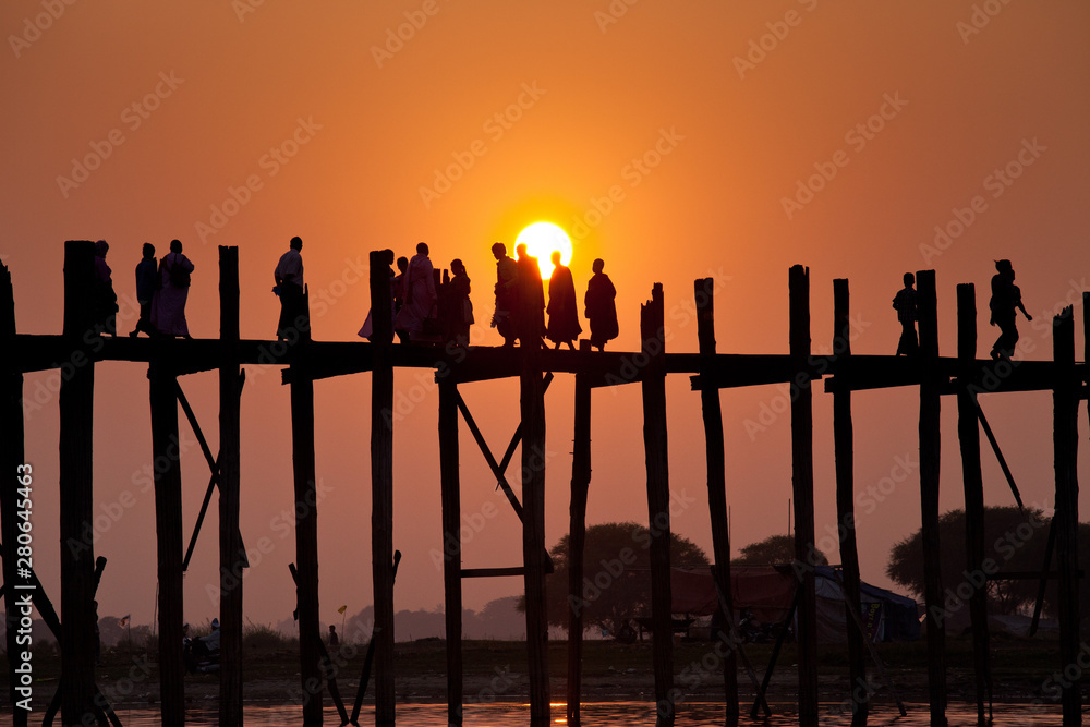 日落时分，缅甸曼德勒地区阿马拉普拉乌贝恩大桥上的人物剪影。缅甸。The longe