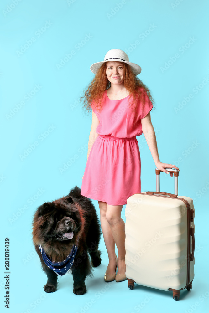 可爱的松狮犬和带彩色行李箱的年轻女子