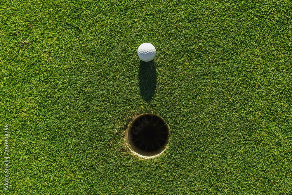 绿色草地上有洞和阳光的高尔夫球