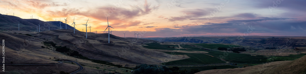 Beautiful Panoramic Landscape View of Wind Turbines on a Windy Hill during a colorful sunrise. Taken