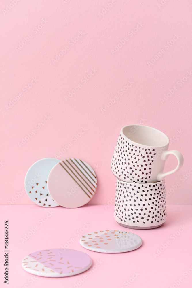Ceramic cups with plates on color background