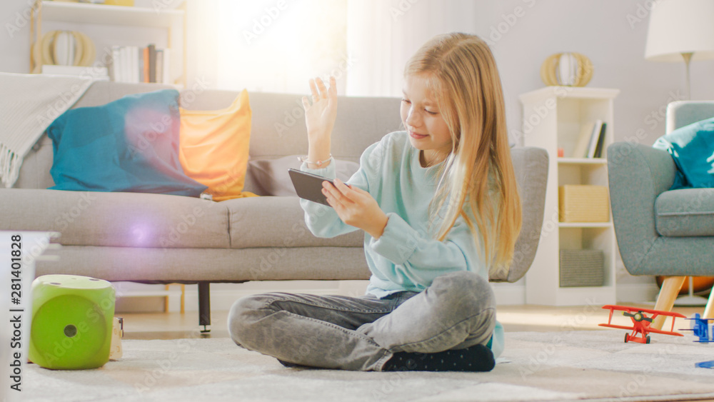 聪明可爱的女孩坐在地毯上用智能手机玩电子游戏，拿着并使用手机P