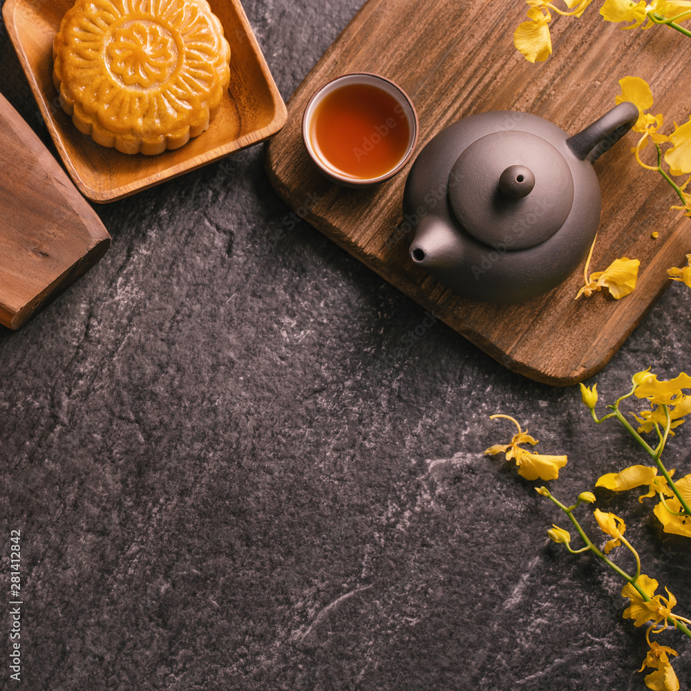 Mid-Autumn Festival traditional food concept - Beautiful Moon cake on black slate table with tea, pa