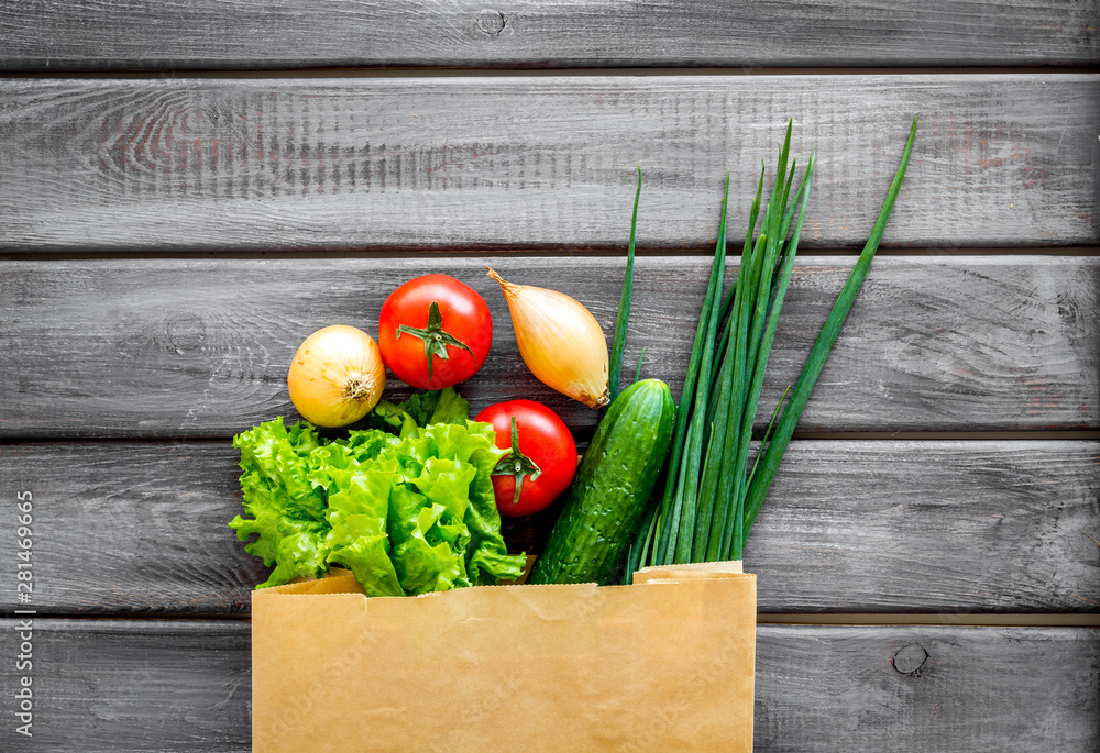 Buying fresh vegetables in paper bag on wooden background top view