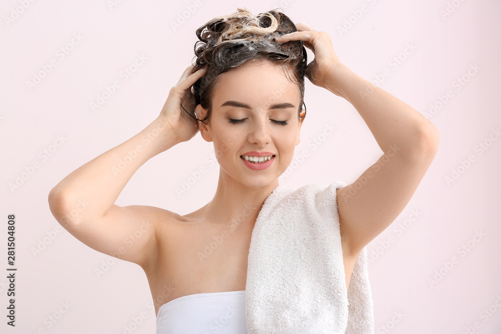 美丽的年轻女子在浅色背景下洗头