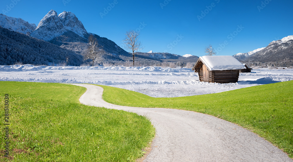 Fotomontage Klimawandel, grüne Wiese mit Kurvenweg und Winterlandschaft im Gebirge mit Hütte