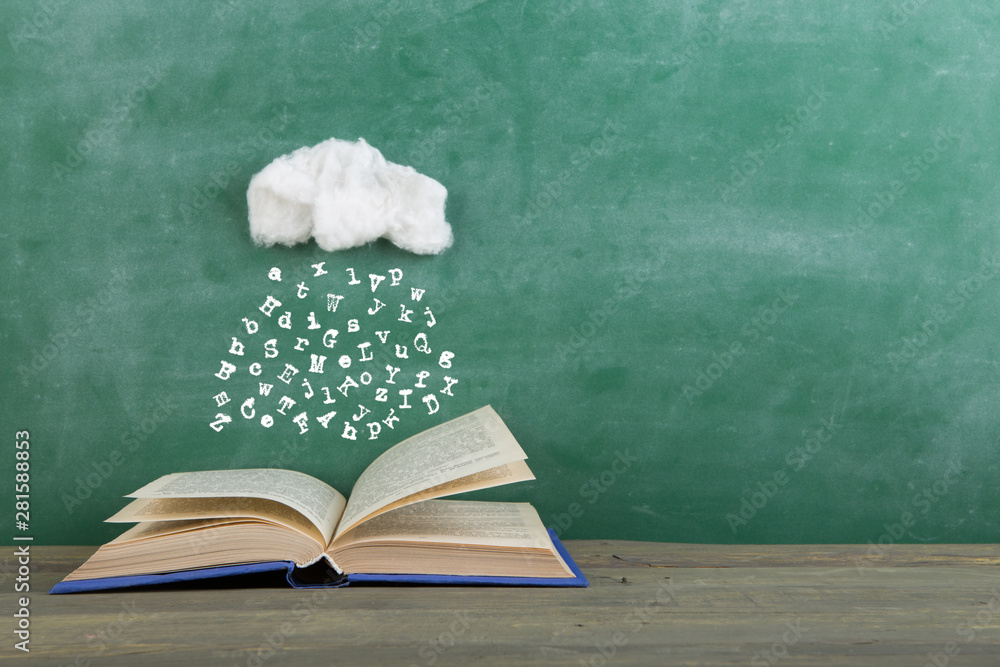 教育和阅读创意概念——信件的雨水落入一本打开的书中，灵感来自w