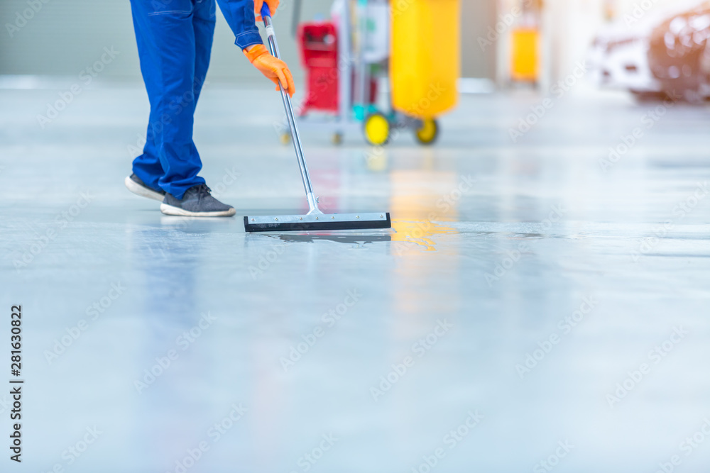 Car mechanic repair service center cleaning using mops to roll water from the epoxy floor. In the ca