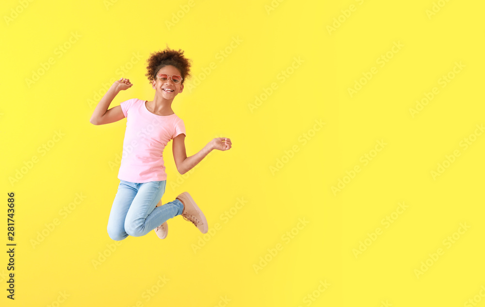 穿着彩色背景牛仔裤的跳跃的非裔美国女孩