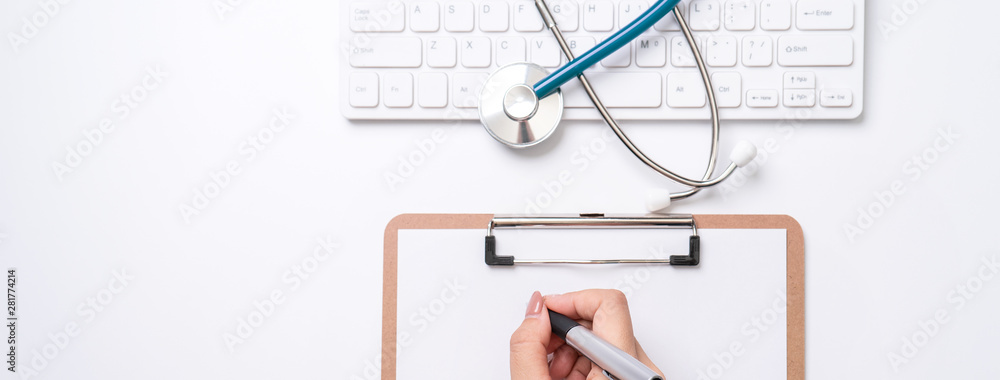 女医生用听诊器在白色工作台上的剪贴板上写病历，