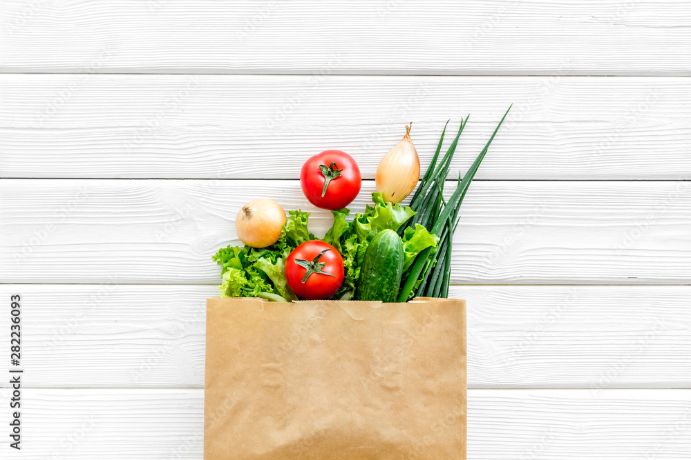 白色木质背景纸袋装新鲜蔬菜的健康食品俯视图