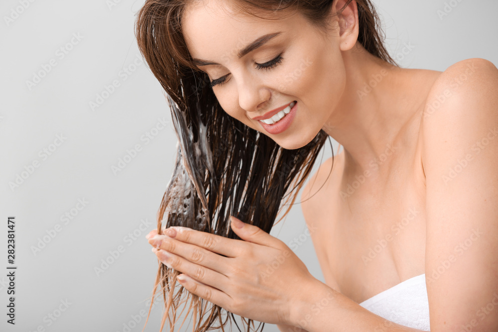 美丽的年轻女子在灰色背景下洗头
