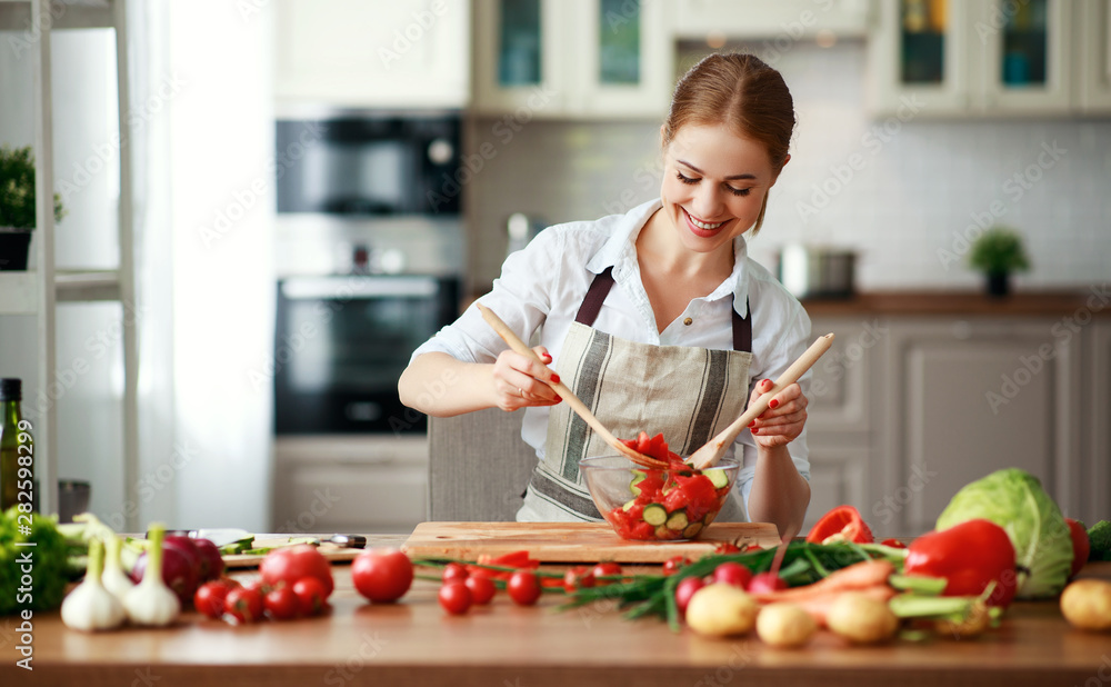 happy woman preparing vegetable salad in kitchen.