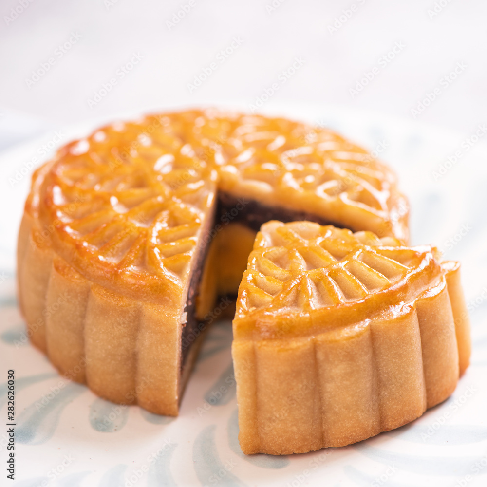 Mid-Autumn Festival traditional food concept - Beautiful cut moon cake on blue pattern plate on whit