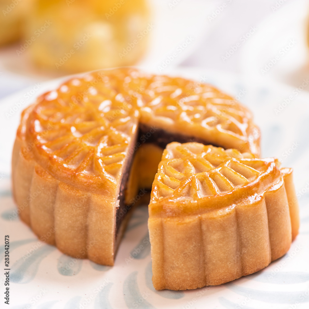 Mid-Autumn Festival traditional food concept - Beautiful cut moon cake on blue pattern plate on whit