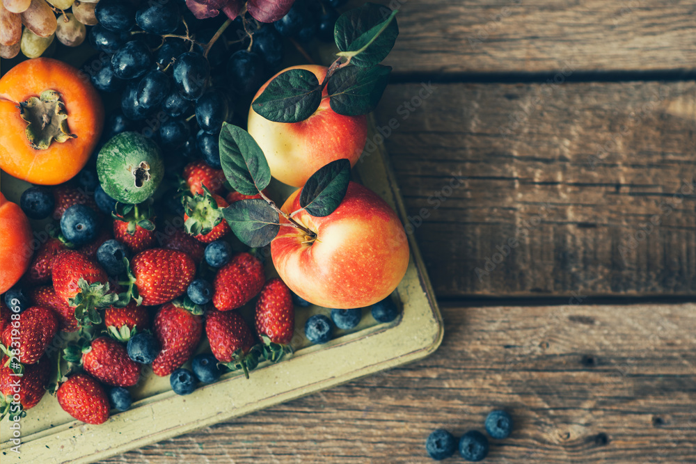 木托盘中的健康食品清洁饮食选择：草莓、蓝莓、苹果、葡萄、柿子