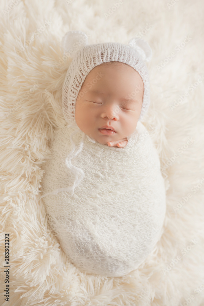 Adorable newborn baby sleeping in cozy room. Cute happy infant baby portrait with sleepy face in bed