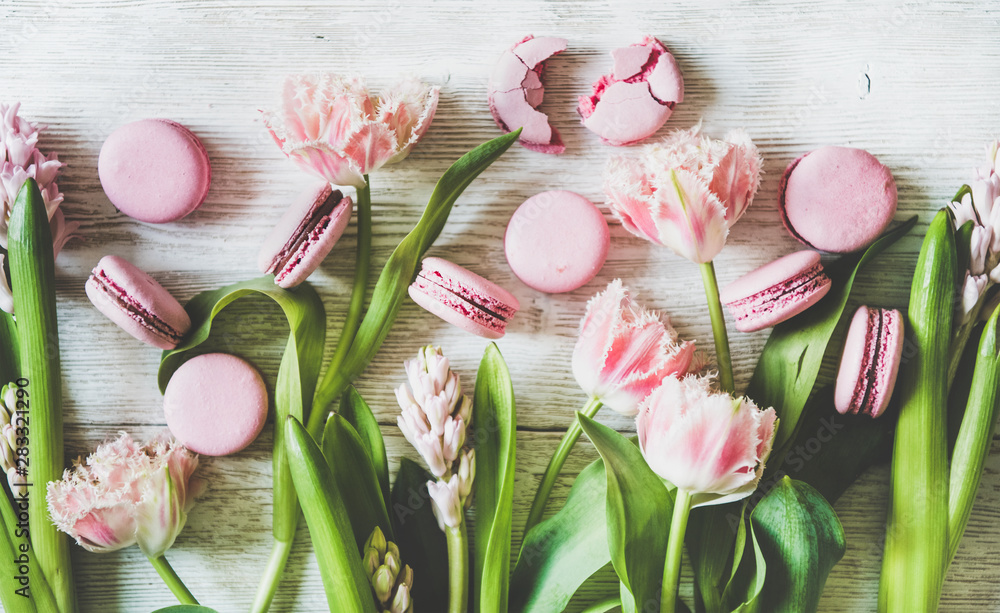 白色木质背景上的甜粉色马卡龙饼干和新鲜的春花，顶部vi