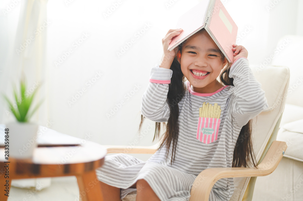 快乐的小女生，头上戴着书。回到学校的概念。