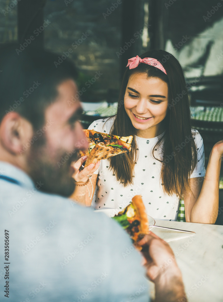 阳光明媚的夏天，年轻快乐的高加索夫妇坐在意大利美食咖啡馆的桌子旁吃披萨