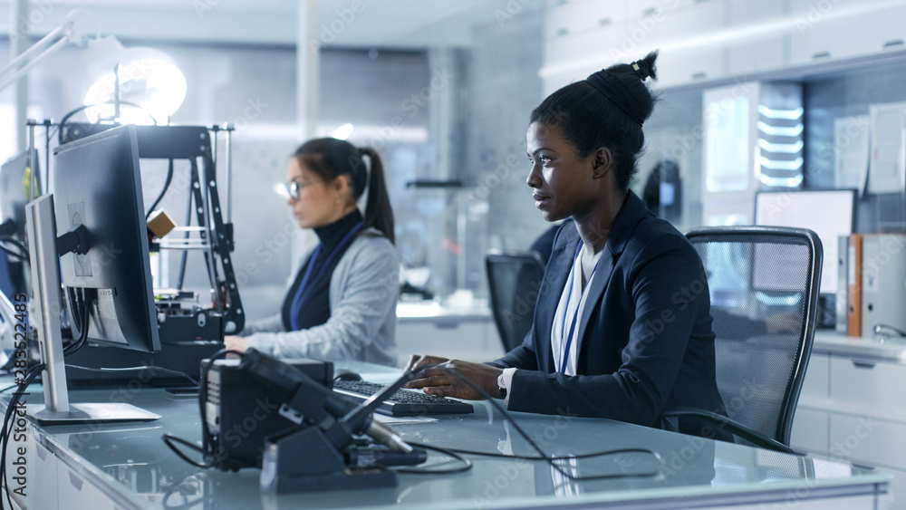 黑人女科学家在研究中心与同事一起在电脑上工作。她的同事是