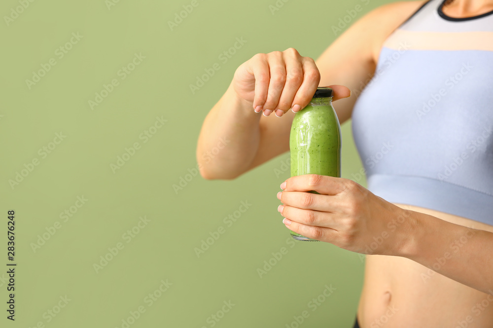 运动女性，彩色背景上有一瓶美味的绿色奶昔