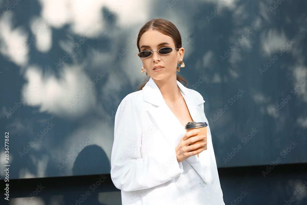 时尚的年轻女人在户外喝咖啡