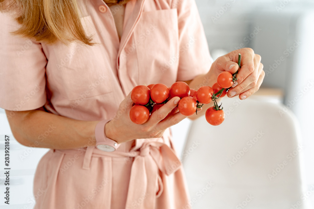 拿着成熟樱桃番茄树枝的女人，特写