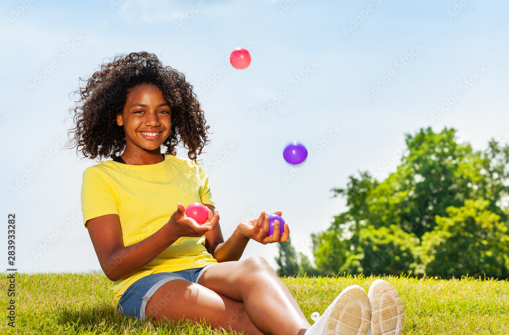 女孩在公园草坪上玩杂耍，面带微笑