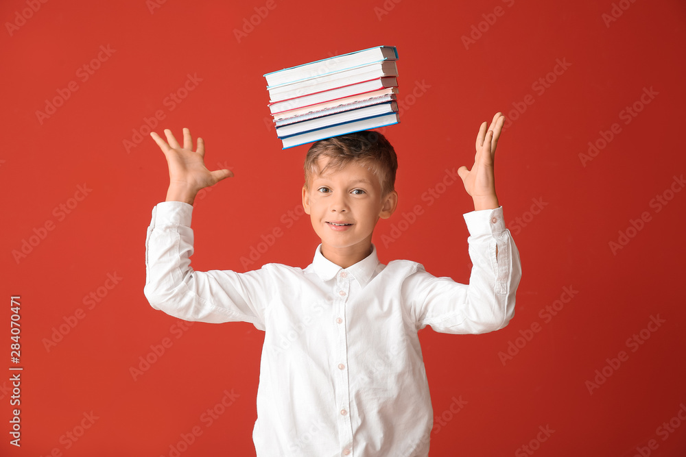 Little schoolboy with books on color background