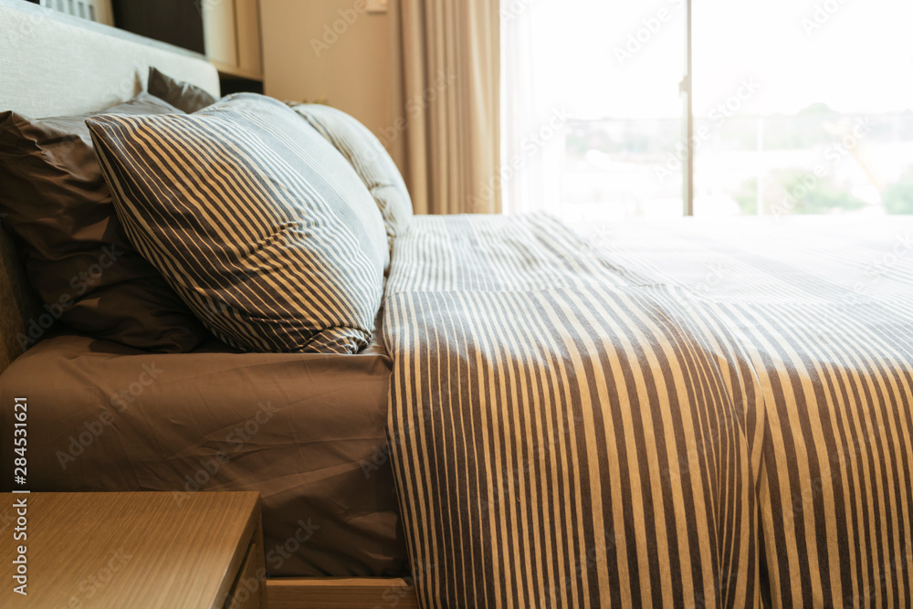 床上的近距离白色米色软枕头和毯子卧室室内设计概念。床上女仆豪华