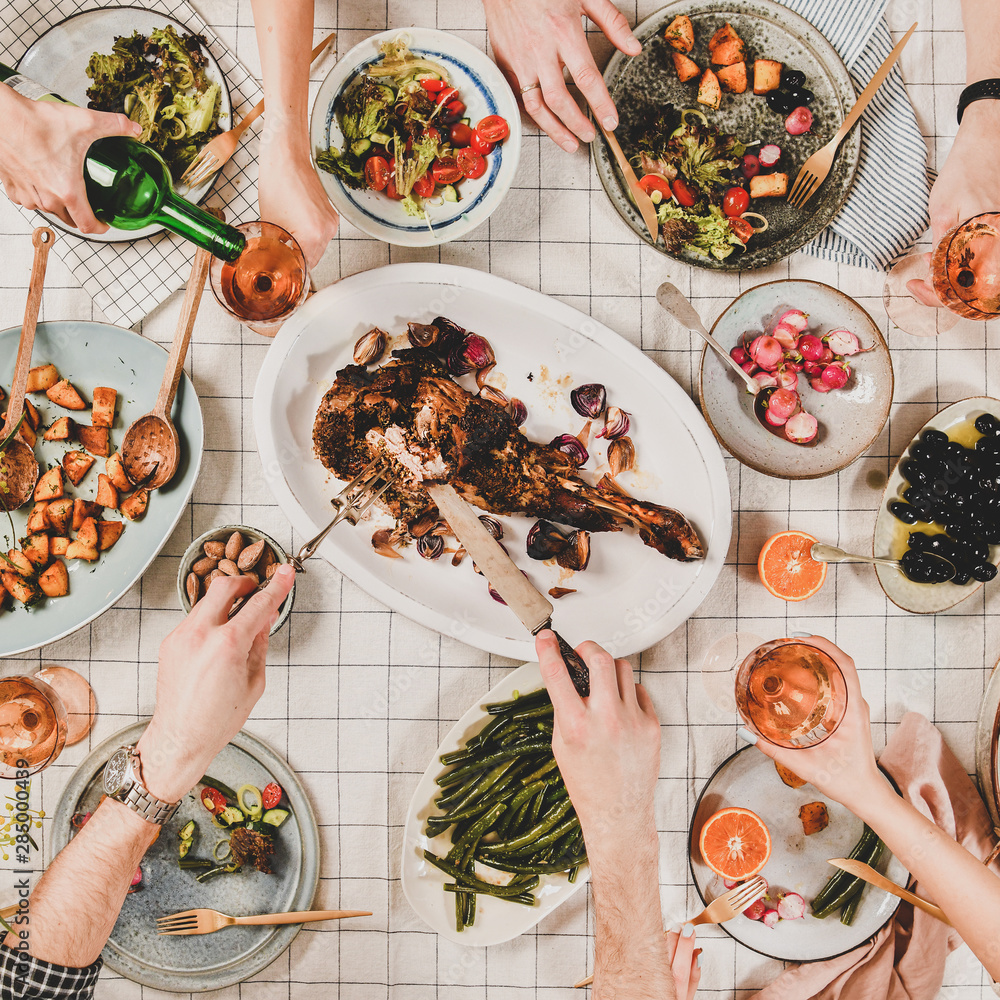 家人或朋友聚在一起吃晚餐。吃羊肩肉、沙拉、蔬菜的人平躺在地上