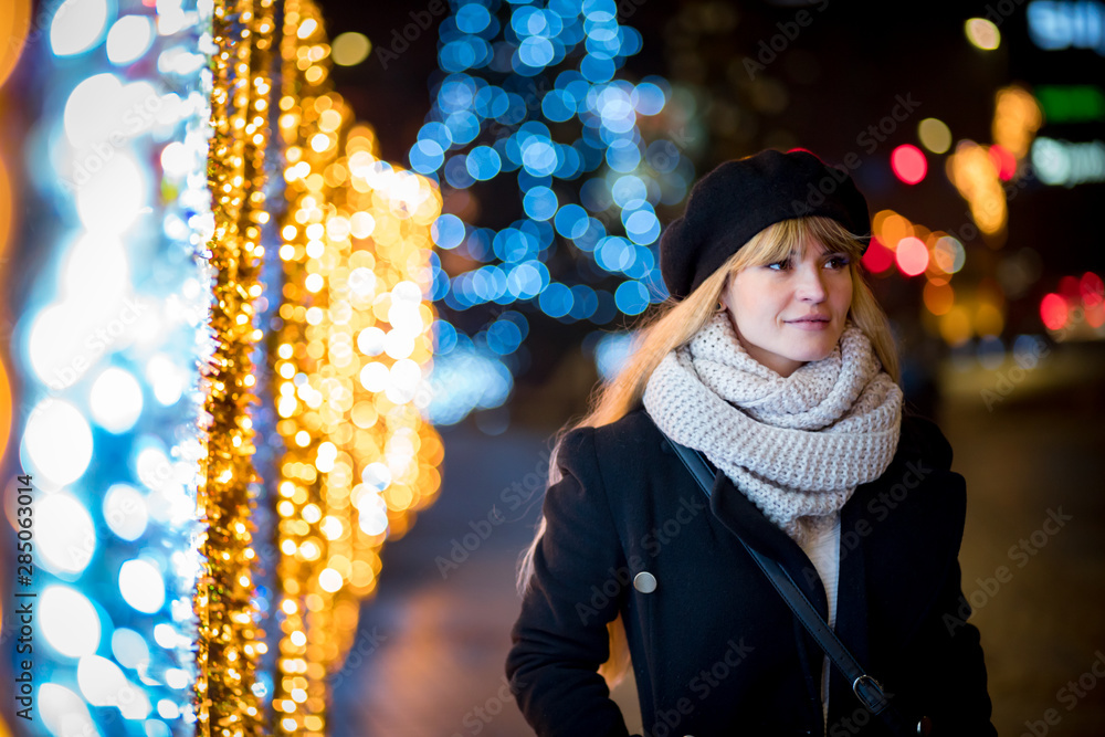 Young woman walking along illuminated alley during Christmas