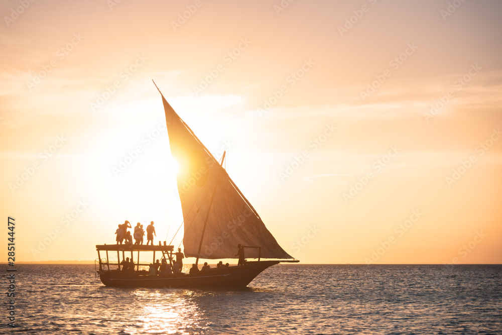 Sailboat in ocean at sunset in summer. Tropical landscape with silhouette of the people in boat, ora