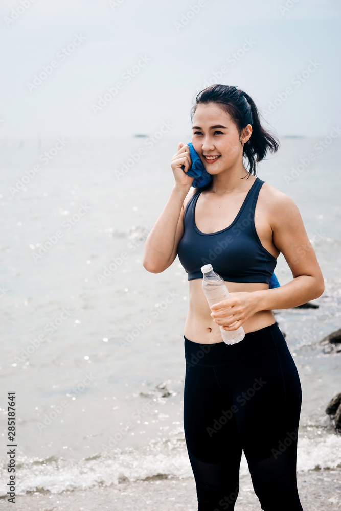一个美丽的亚洲女人在早上跑步喝水。锻炼和户外运动
