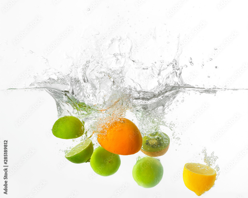 白色背景下不同的水果落入水中