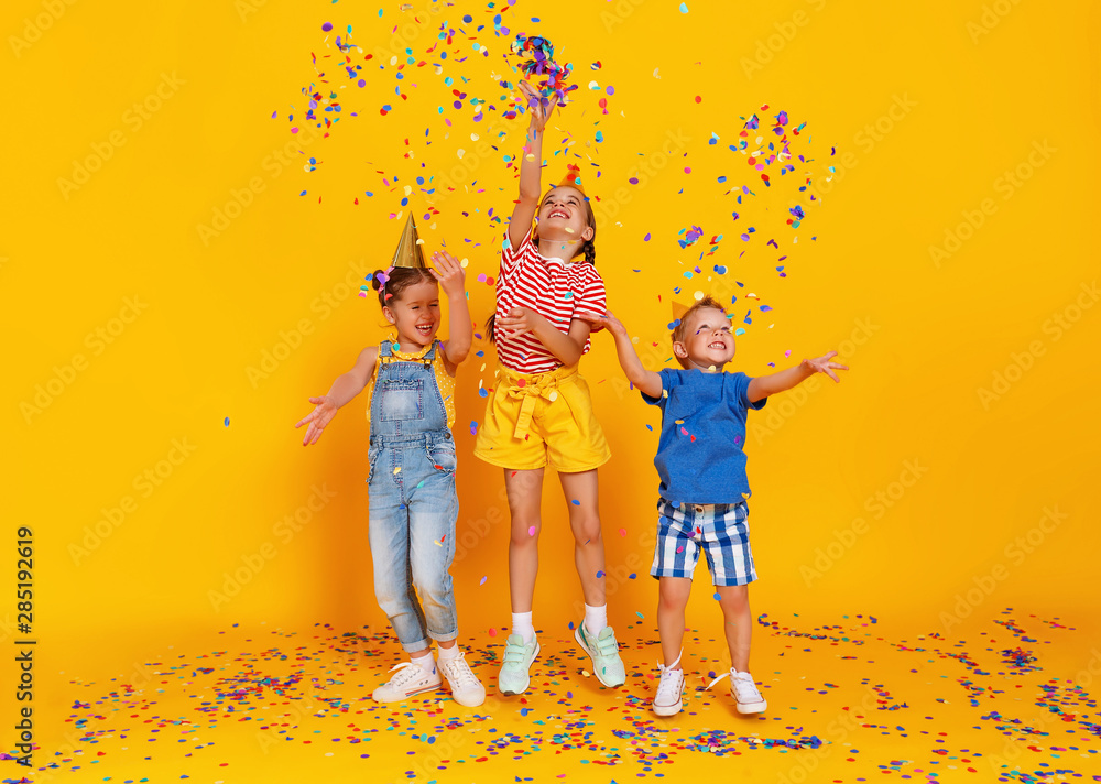 节日快乐的孩子们在黄色五彩纸屑中跳跃