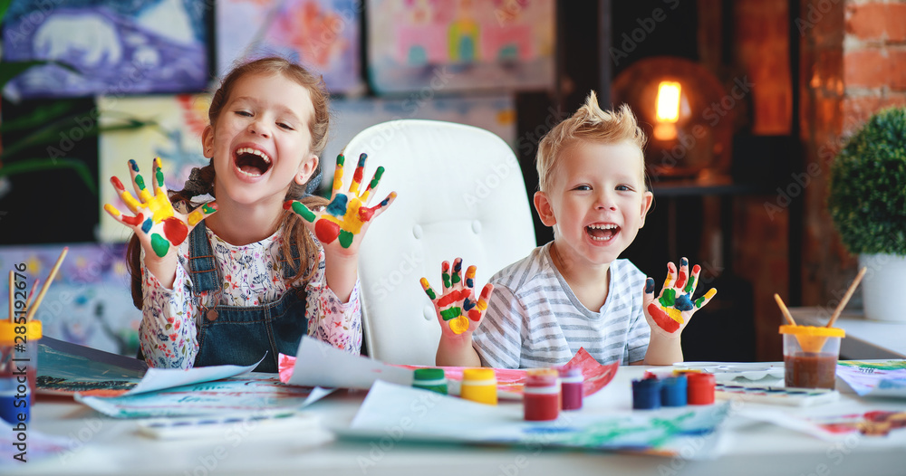 有趣的孩子女孩和男孩画画，笑得手被油漆弄脏了。