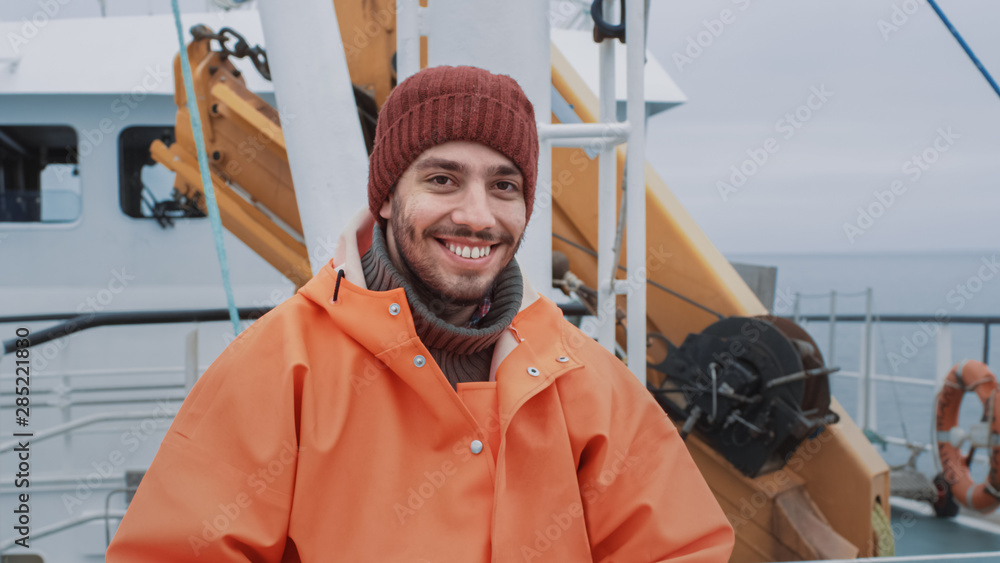 身穿明亮防护服的渔夫在商业渔船上微笑的肖像