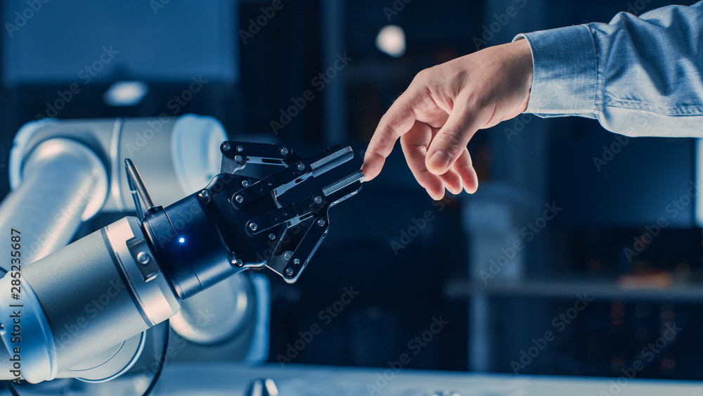 未来主义机器人手臂在人类和人工智能统一手势中触摸人手。Co