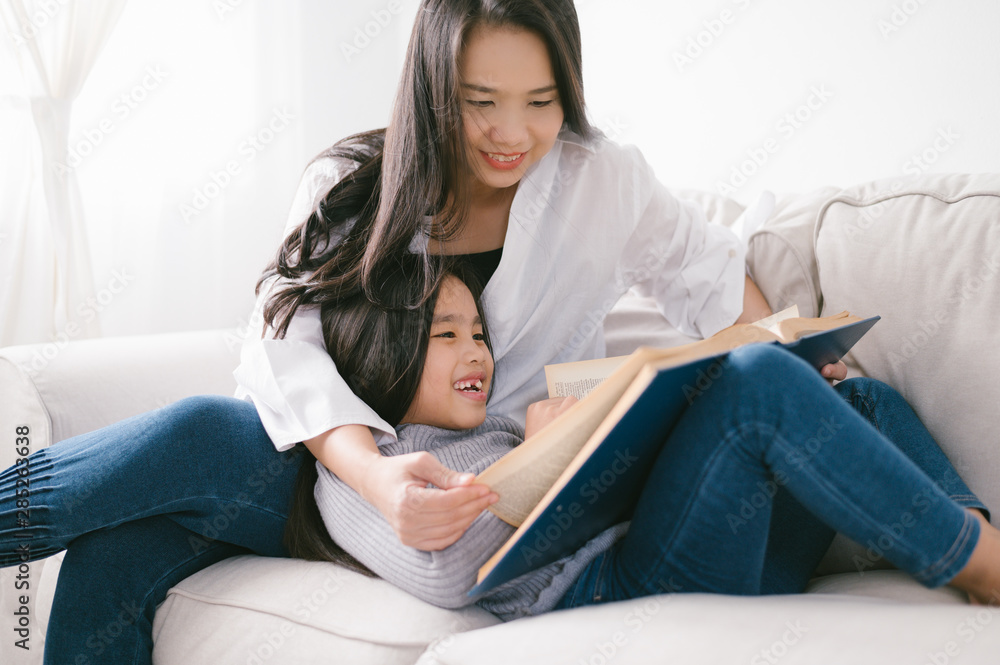快乐的亚洲小女孩在家客厅的桌子上看书。家庭活动