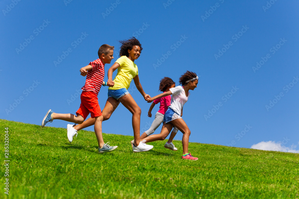 四个快乐、长相各异的孩子在草坪上奔跑