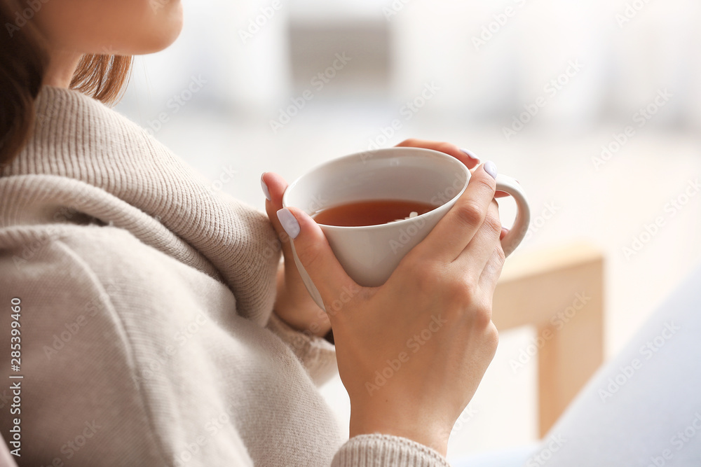 Beautiful young woman drinking tea at home, closeup
