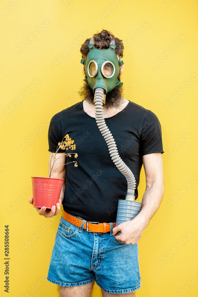 一个悲伤的男人的画像，黄色背景上戴着防毒面具和干花盆。可怜的ec的概念