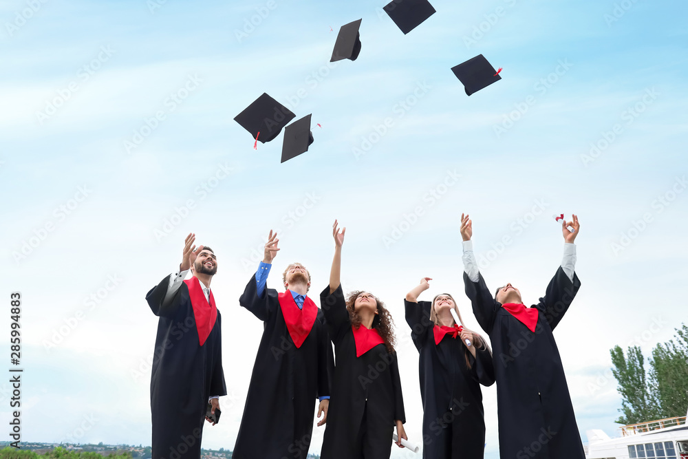 穿着学士长袍的快乐学生在户外扔毕业帽