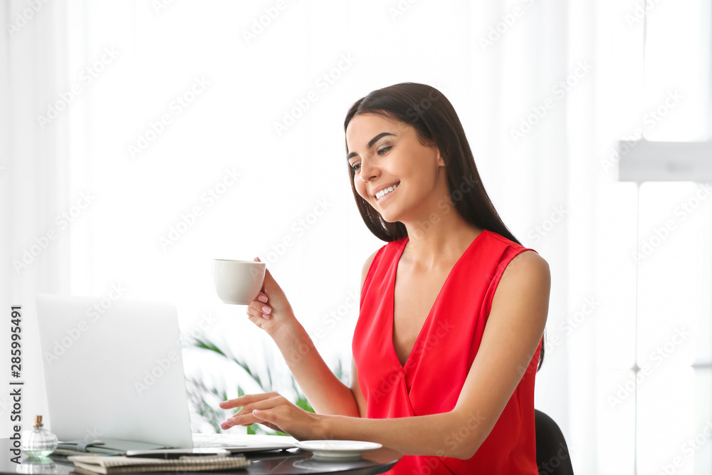 女博主拿着笔记本电脑在咖啡馆喝咖啡